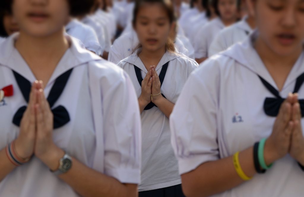 TO GO WITH 'THAILAND-POLITICS-ROYALS-EDUCATION' by Delphine THOUVENOT This picture taken on December 2, 2014 shows Thai female students standing in lines and offering Buddhist prayers in the courtyard of the Satriwithaya school in downtown Bangkok at the start of their school day. Thailand's military rulers are pushing a fresh set of values on students emphasising love for the monarchy and a deference to authority which critics say is symptomatic of both the junta's authoritarianism and the country's stultifying education system. AFP PHOTO/Christophe ARCHAMBAULT