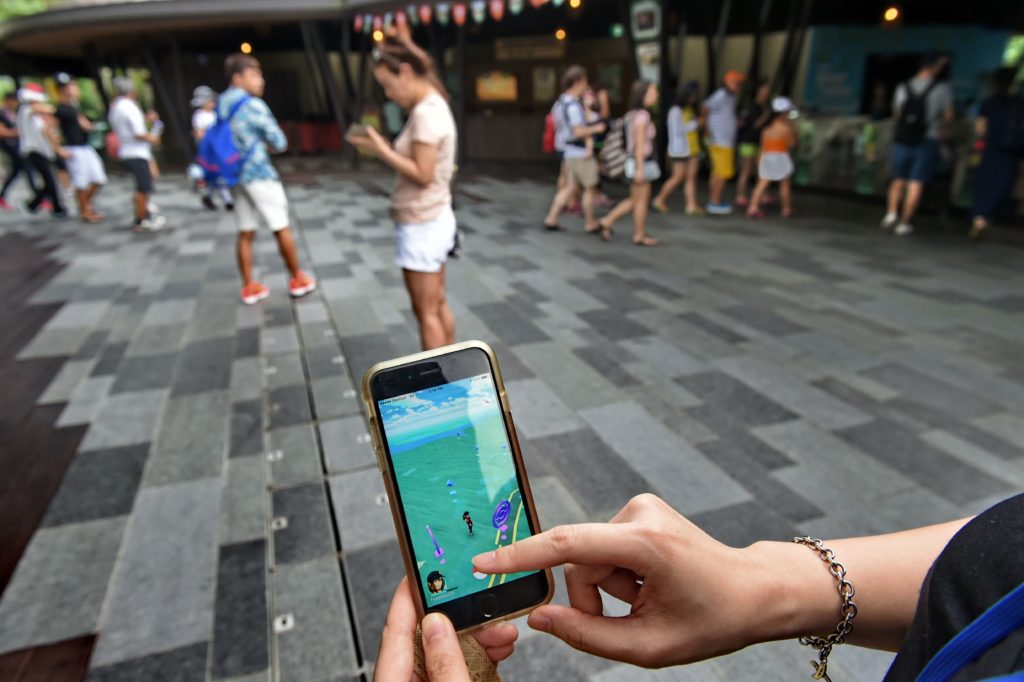 A Singaporean plays Pokemon Go outside the zoological garden in Singapore on August 7, 2016. Pokemon Go was available in nine countries on August 6, including Singapore. The Singapore zoo has even come up with a map for users on where to find Pokenmon on its ground. / AFP PHOTO / ROSLAN RAHMAN