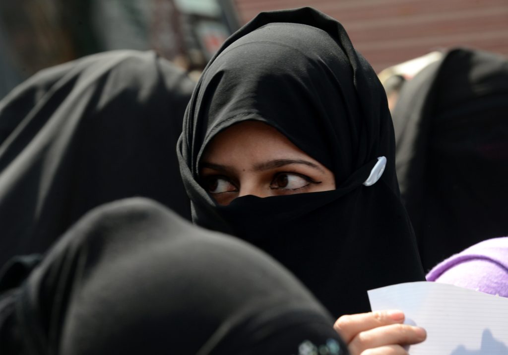 An activist from the Muslim Khawateen Markaz (MKM) organisation looks on as others shout anti-Indian slogans during a protest in Srinagar on March 20, 2014. Police detained activists of MKM, a Kashmiri women's separatist party, as they held a protest to demand the release of Kashmiri men who have been lodged in different jails in India since a rebellion broke out in the region at the end of 1989. AFP PHOTO/Tauseef MUSTAFA