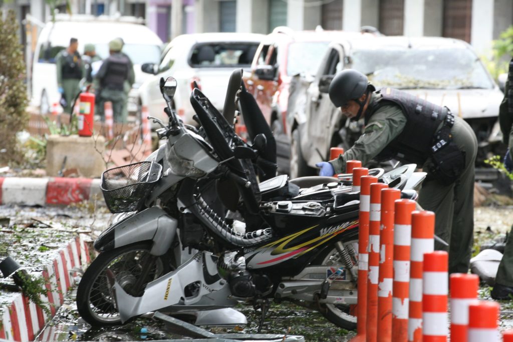 A Thai soldier searches parked motorcycles at the site of a bombing from the night before outside of a hotel, in the southern province of Pattani on August 24, 2016. A large car bomb blew up outside a hotel in Thailand's insurgency-plagued southern region late, killing one and wounding more than 30 people, some of them critically, police said. Although the area is not popular with tourists, the country has been on edge since a string of small but coordinated explosions earlier this month struck resort towns further north. / AFP PHOTO / TUWAEDANIYA MERINGING