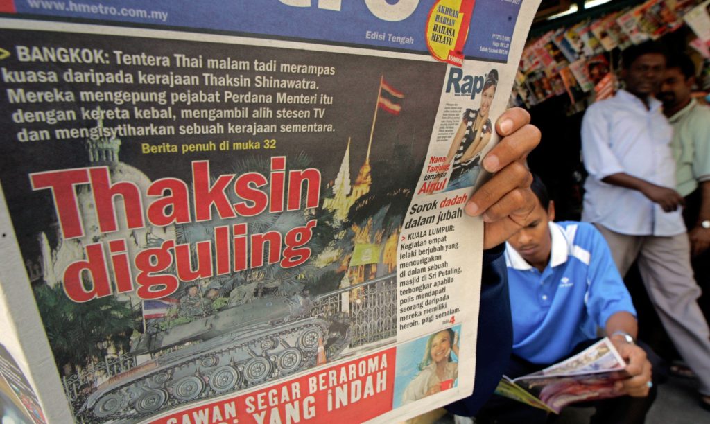 A Malaysian man reads newspaper reporting the coup d'et in Thailand at a shop in downtown Kuala Lumpur, 20 September 2006. Thailand's new military rulers tightened their grip 20 September after an overnight coup, imposing strict controls on the media and banning public gatherings in what they said was a bid to restore order. AFP PHOTO/TEH ENG KOON / AFP PHOTO / TEH ENG KOON