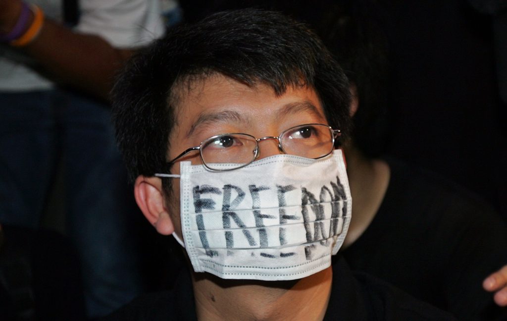 Thai student wearing a mask reading "Freedom" takes part in a protest against the country's military coup leaders in front of a shopping mall in Bangkok, 22 September 2006. A group of Thai students and democracy activists protested against the late 19 September military's bloodless coup against prime minister Thaksin Shinawatra, defying the junta's ban on political rallies. AFP PHOTO / MIKE CLARKE / AFP PHOTO / MIKE CLARKE