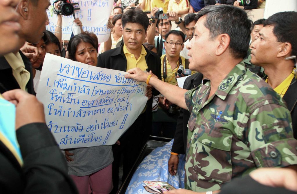 General Sonthi Boonyaratglin (R), the head of the Thai junta, listens complaints of protestors who blocked his way by placing the dead body of a Buddhist woman (bottom) shot dead and burned by suspected separatist rebels in Thailand's restive Yala province, 11 April 2007. Around 200 people paraded the charred remains of a Buddhist woman through the streets of Yala town to protest the unending violence in Thailand's restive Muslim-majority south.  AFP PHOTO / Muhammad SABRI / AFP PHOTO / MUHAMMAD SABRI