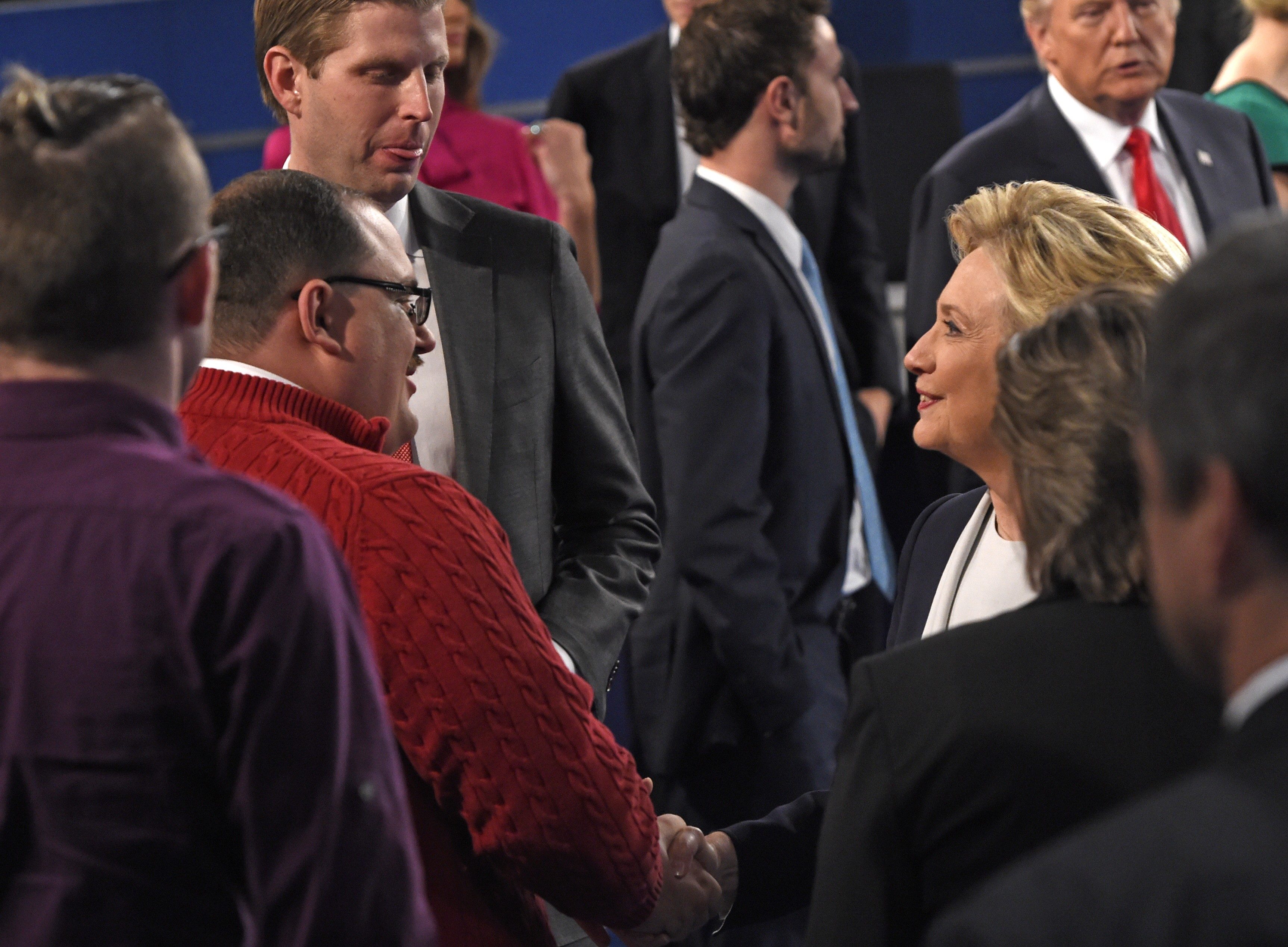 (FILES) In this file photo dated October 9, 2016 US Democratic Presidential nominee Hillary Clinton (R) shakes hands with Ken Bone following the second presidential debate with Republican nominee Donald Trump (far R background) at Washington University in St. Louis, Missouri. As the mud flew at Donald Trump and Hillary Clinton's second presidential debate Sunday, the American everyman became an instant celebrity by calmly asking a question about energy policy. Bone -- even his sturdy name has been a source of amusement on social media -- had been picked to represent undecided voters at the town hall-style debate in St Louis, Missouri. His heft, poise and polite manner offered a brief but refreshing respite from the 90-minute slug-fest between the Republican and Democratic candidates. / AFP PHOTO / POOL / SAUL LOEB / TO GO WITH AFP STORY "Ken Bone, everyman hero in a tawdry US campaign"