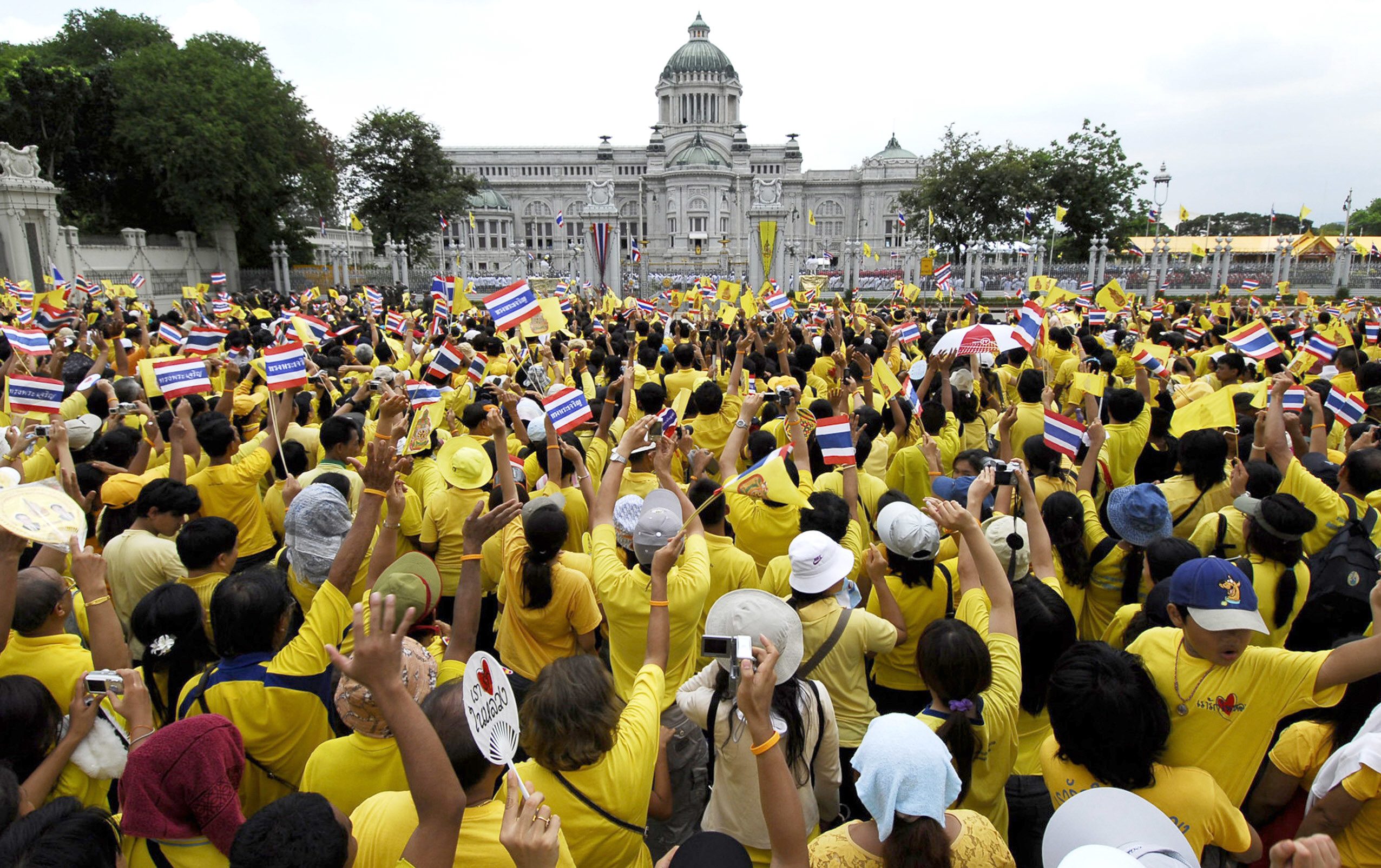 Thousands of Thais in yellow T-shirts wave to their beloved King Bhumibol Adulyadej in front of the Dusit Palace in Bangkok, 09 June 2006. Thai King Bhumibol Adulyadej called for unity among his people after months of political turmoil, in a speech to mark his 60th anniversary on the throne. Half a million Thais wearing yellow to honor the King swarmed into central Bangkok hoping to catch a rare glimpse of the monarch on the 60th anniversary of his rule. RESTRICTED TO EDITORIAL USE AFP PHOTO/ROYAL PALACE/HO / AFP PHOTO / ROYAL PALACE / STR