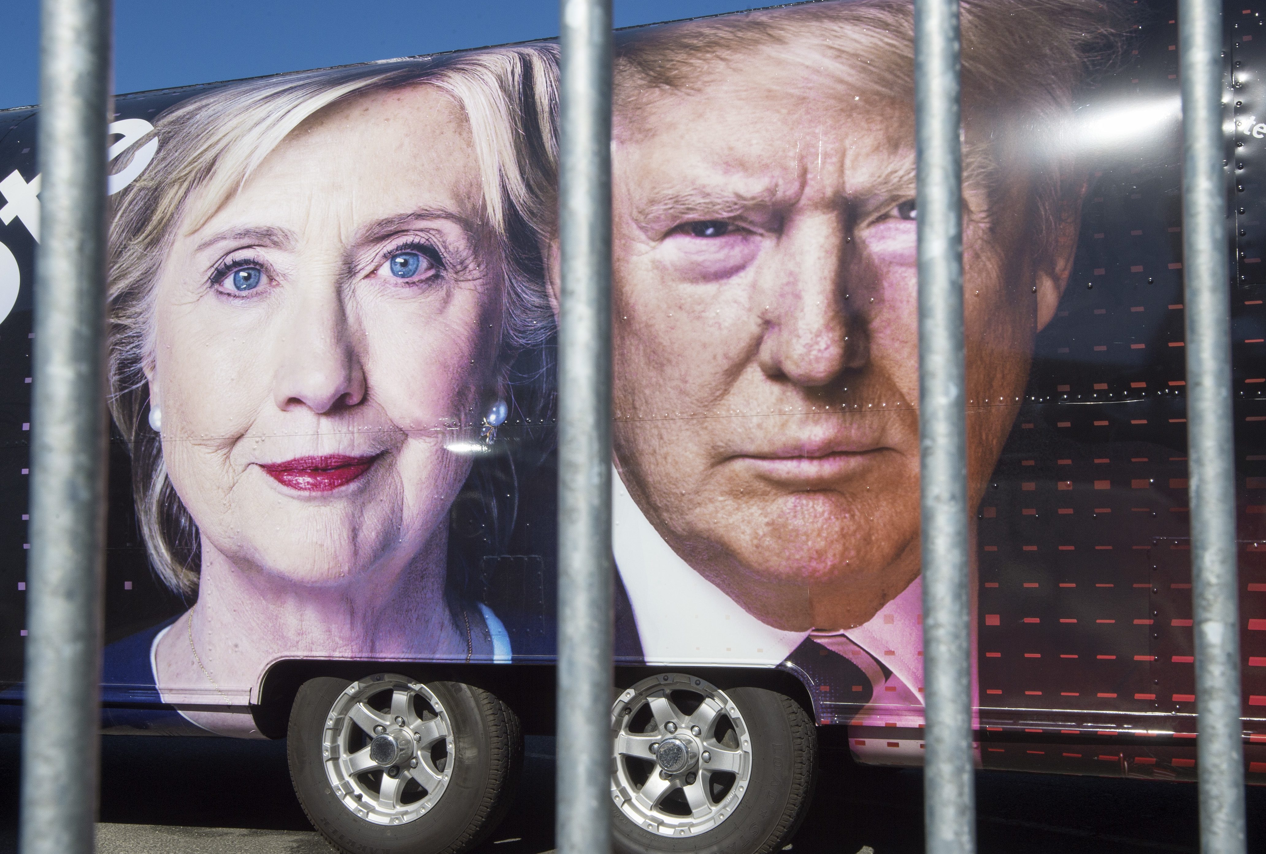 Large images of Democratic nominee Hillary Clinton and Republican nominee Donald Trump are seen on a CNN vehicle, behind asecurity fence, on September 24, 2014, at Hofstra University, in Hempsted, New York. The university is the site of the first Presidential debate on September 26, between Democratic nominee Hillary Clinton and Republican nominee Donald Trump. / AFP PHOTO / PAUL J. RICHARDS