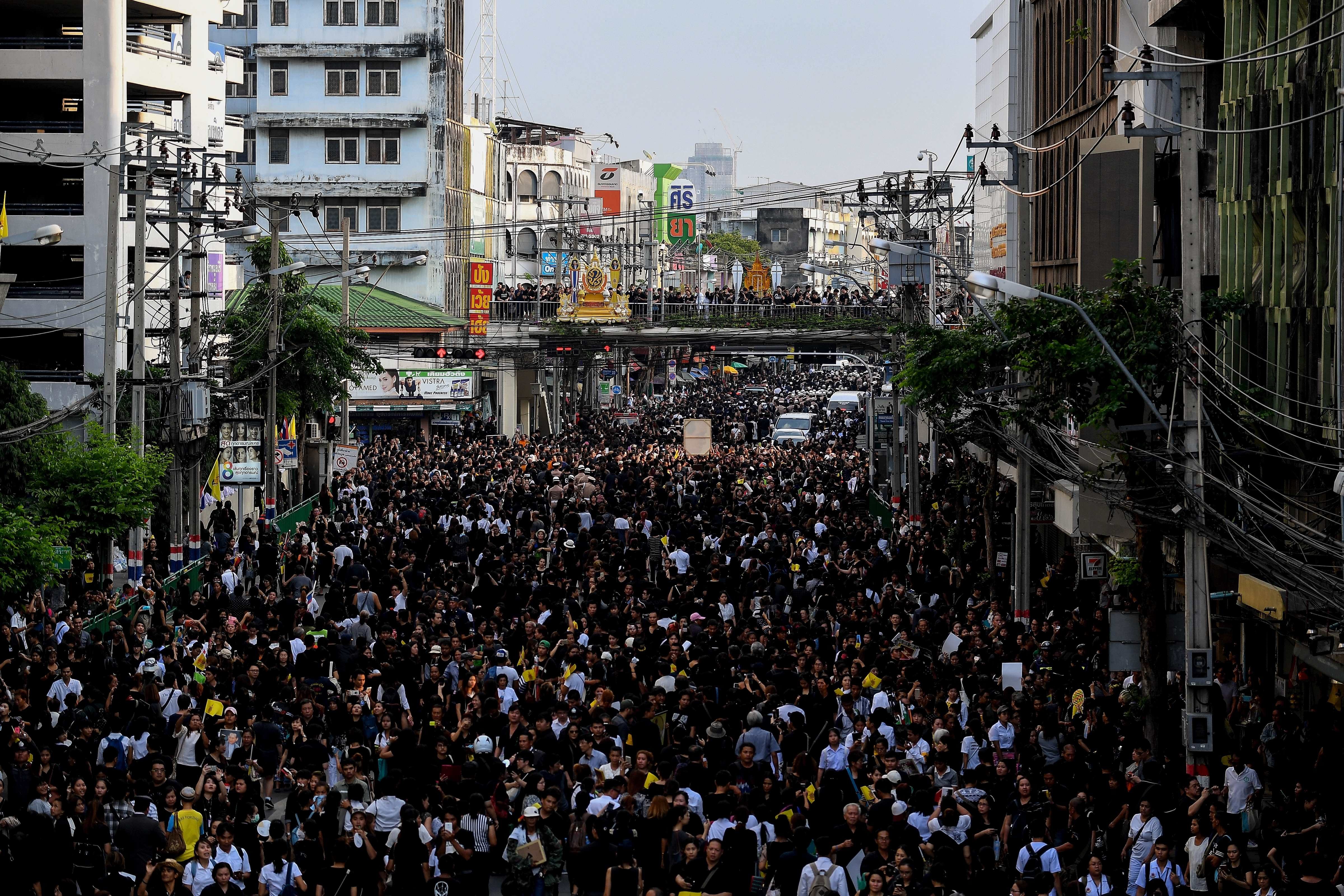 A general view shows thousands of people walking on the road after the procession of Thai King Bhumibol Adulyadej's body left the Siriraj Hospital for his palace in Bangkok on October 14, 2016. Bhumibol, the world's longest-reigning monarch, passed away aged 88 on October 13, 2016 after years of ill health, removing a stabilising father figure from a country where political tensions remain two years after a military coup. / AFP PHOTO / MANAN VATSYAYANA