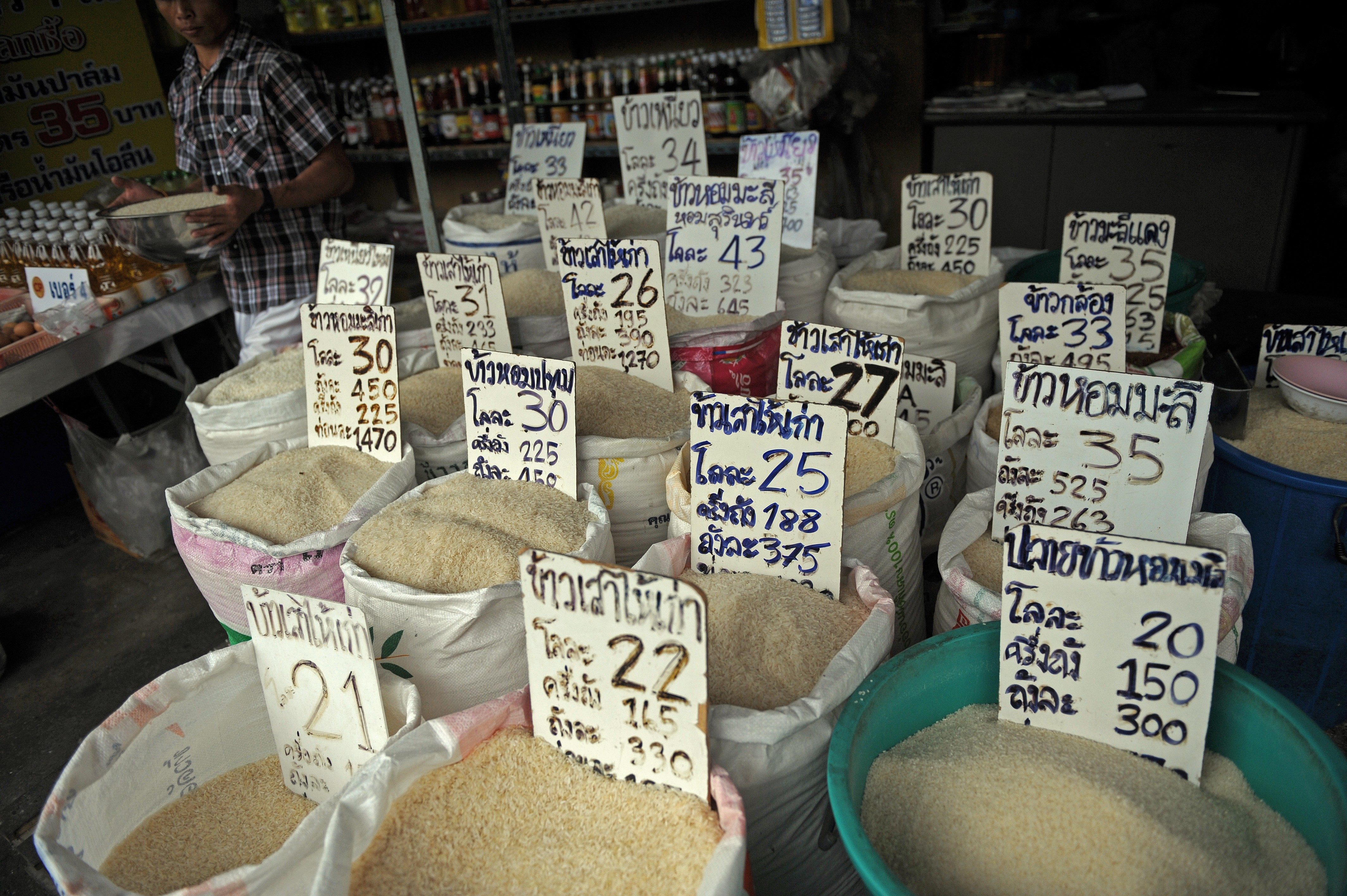 A Thai vendor carries a variety of rice to refill a bag at his shop at a market in Bangkok on September 25, 2011.  A populist policy aimed at boosting the incomes of Thai farmers has raised fears of global rice price turbulence, but experts say the kingdom could just be hurting itself.   AFP PHOTO/Christophe ARCHAMBAULT / AFP PHOTO / CHRISTOPHE ARCHAMBAULT