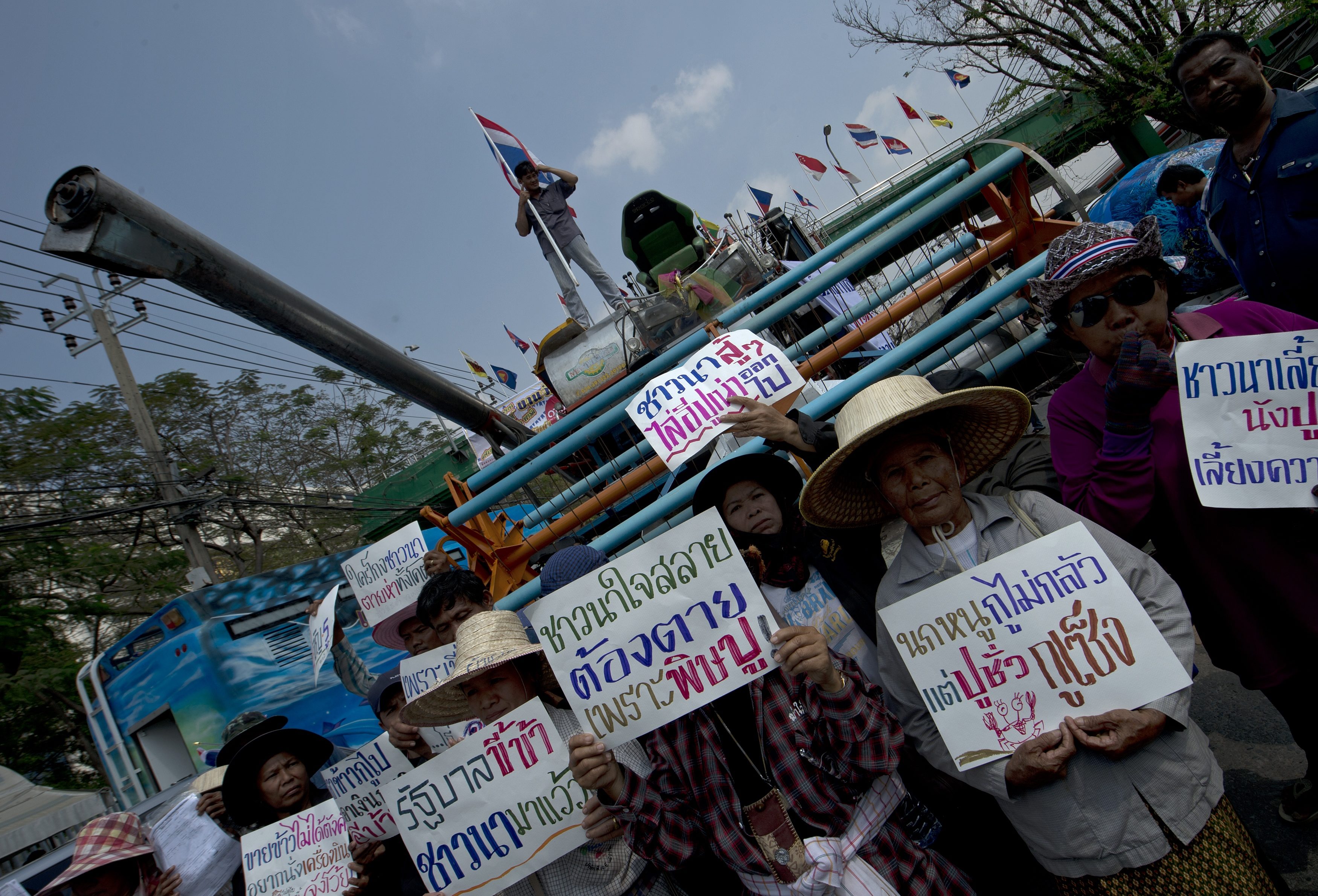 Thai farmers hold protest palcards next to a tractor as they protest the governments delayed payments for rice submitted to the pledging scheme, at the Commerce Ministry in Nonthaburi province on February 6, 2014. Thailand's embattled government on February 6 defended a much-criticised rice subsidy scheme after a Chinese firm cancelled a one million tonne order for stockpiled grain, following a graft probe into Thai officials. AFP PHOTO / PORNCHAI KITTIWONGSAKUL / AFP PHOTO / PORNCHAI KITTIWONGSAKUL