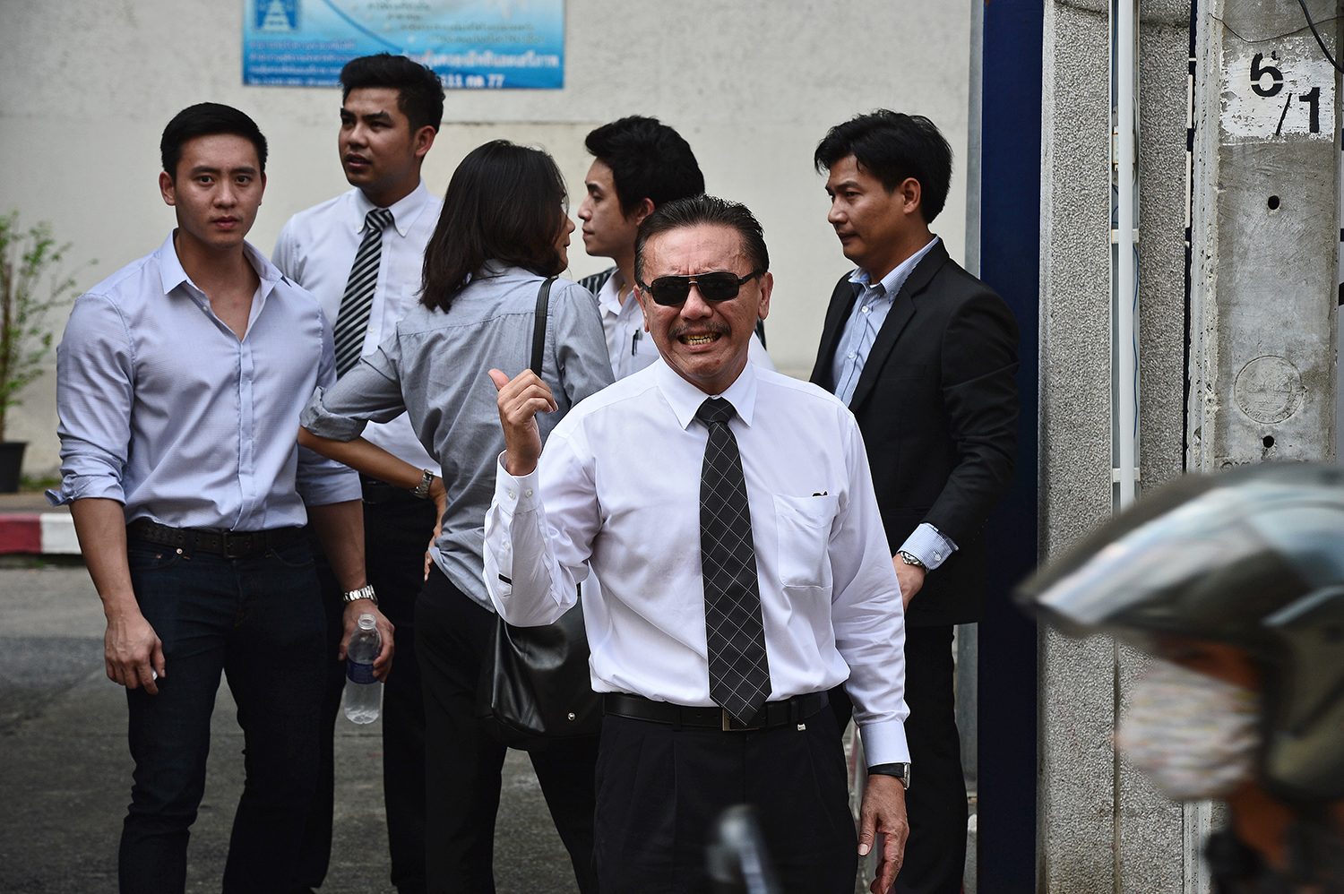 Thai massage parlour impresario turned politician Chuwit Kamolvisit (C) gestures as he waits for a hearing outside a criminal court in Bangkok on October 15, 2015. Chuwit appeared in court on October 15 over accusations he and his associates demolished a group of bars in the heart of Bangkokís nightlife in 2003. If found guilty Chuwit could face up to five years in jail. AFP PHOTO / Christophe ARCHAMBAULT / AFP PHOTO / CHRISTOPHE ARCHAMBAULT